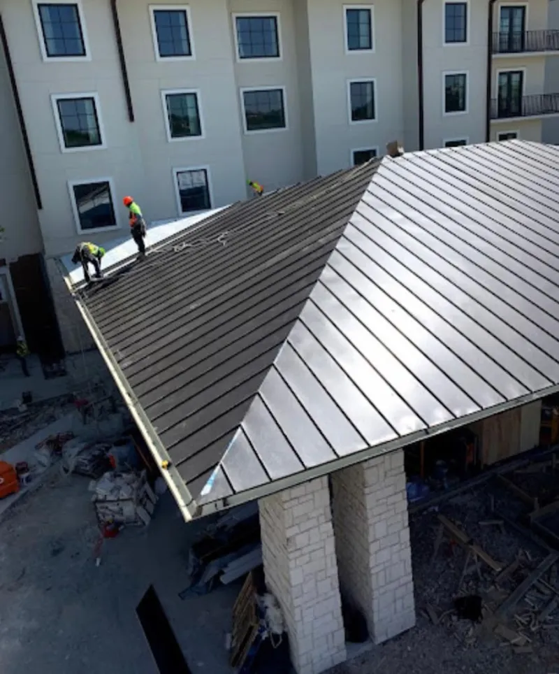 Crew installing standing seam metal roof panels on a commercial project in Kill Devil Hills